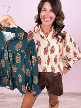 Woman holding a floral blouse with a matching outfit against a pink background
